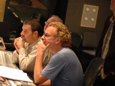 Men seated in front of large mixing board pondering something out of frame