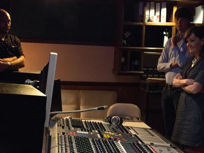 Three people in a dark audio mastering studio
