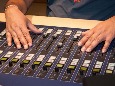 Person's hands on a sound mixing board