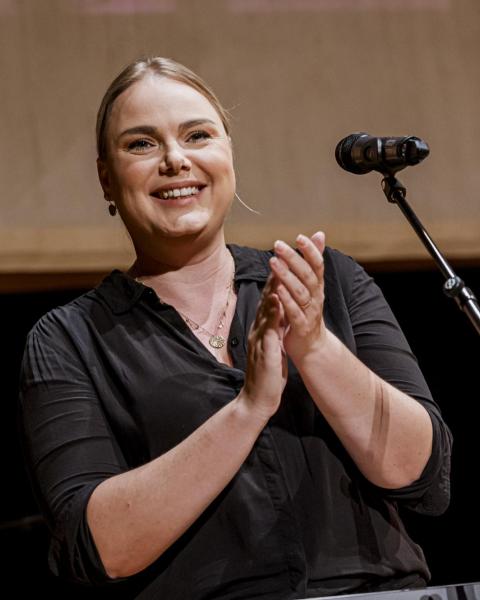 A female music professor applauding in a performance venue