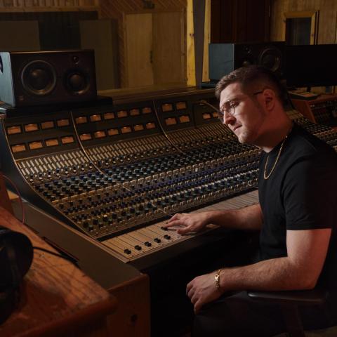 Charlie Rosen '12 behind a mixing board in a studio
