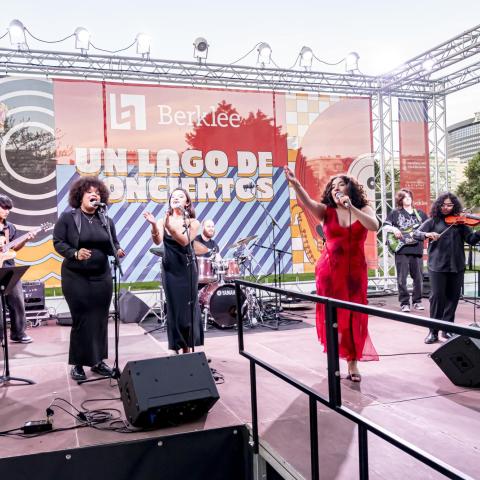 Students perform live at Berklee Valencia’s "Un Lago de Conciertos." The ensemble includes singers, keyboard, guitar, drums, bass, and violin. 