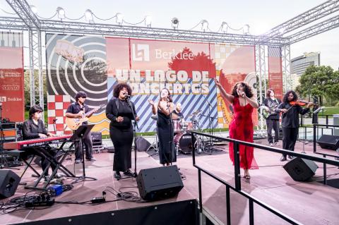 Students perform live at Berklee Valencia’s "Un Lago de Conciertos." The ensemble includes singers, keyboard, guitar, drums, bass, and violin. 